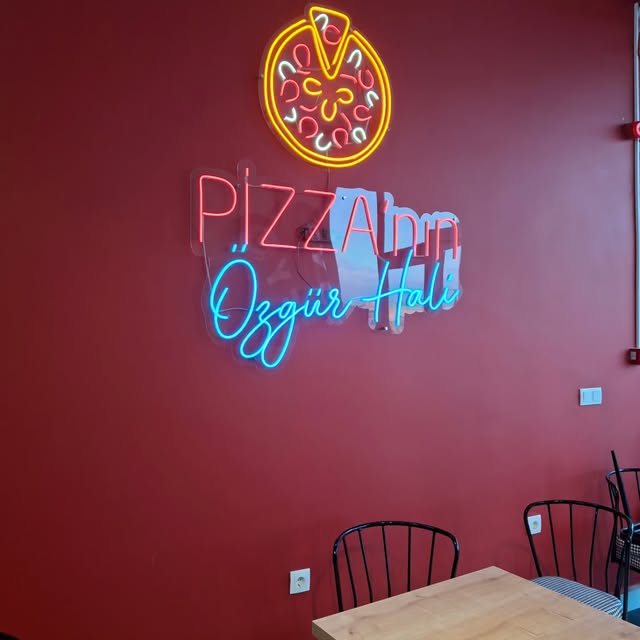 PizzApp iç mekânındaki renkli neon pizza simgesi ve ışıklı yazı